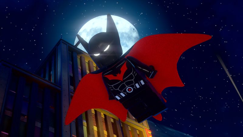 LEGO Batman – Edición Deluxe Figura estilo LEGO de un personaje en traje oscuro con detalles rojos, volando frente a una luna llena en un entorno urbano nocturno.