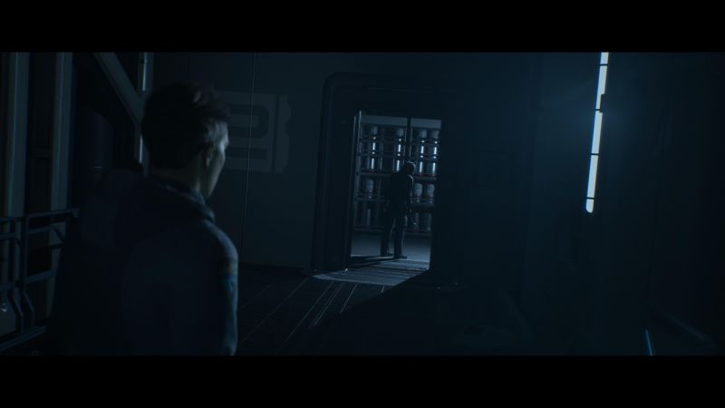 Persona observando a otra dentro de un cuarto iluminado en azul.
