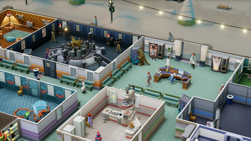 Escenarios de la Expansión Culture Shock Vista superior de las salas del hospital con un set de rodaje que incluye una maqueta de ciudad y un monstruo gigante de utilería.