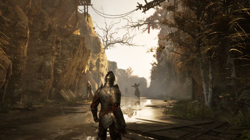 Combate y exploración en Among Shadows para PC Captura de pantalla del gameplay de Among Shadows desde una perspectiva en tercera persona. En el centro aparece un guerrero vistiendo una armadura metálica medieval, caminando por un cañón rocoso con un arroyo en el suelo y vegetación otoñal. A lo lejos se aprecian figuras de criaturas y otros guerreros entre la niebla.
