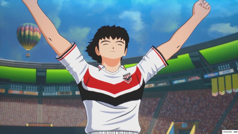 Celebración de gol de Tsubasa Ozora en la cancha Tsubasa Ozora celebrando en el centro de la cancha con ambos brazos en alto y los ojos cerrados tras anotar un gol en el estadio.